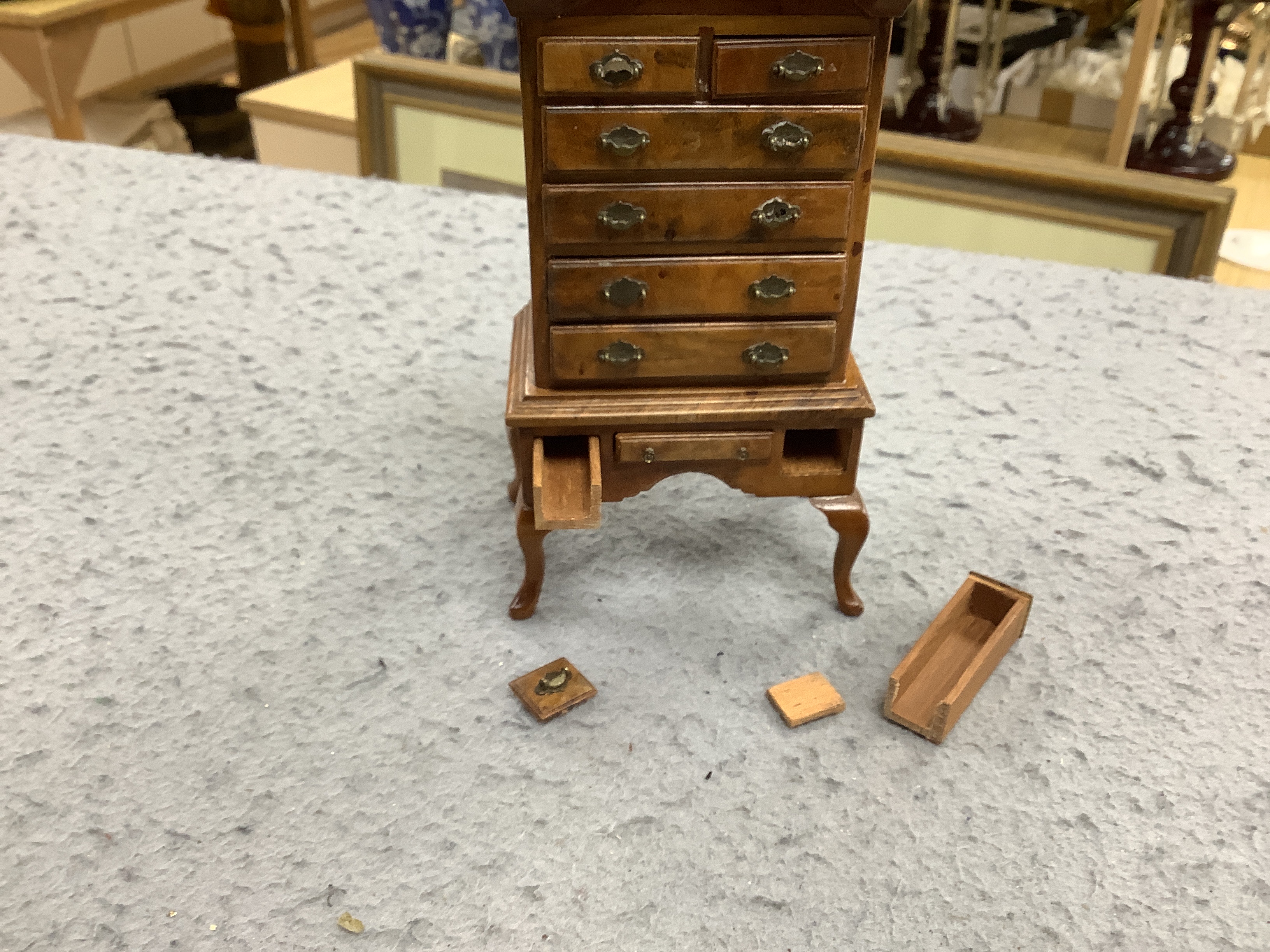 Two pieces of early 20th century miniature furniture - a mid-18th century style walnut bookcase, indistinctly signed on the base (15.5cm high) and a mid-18th century-style walnut chest on stand (16cm high). (Provenance B